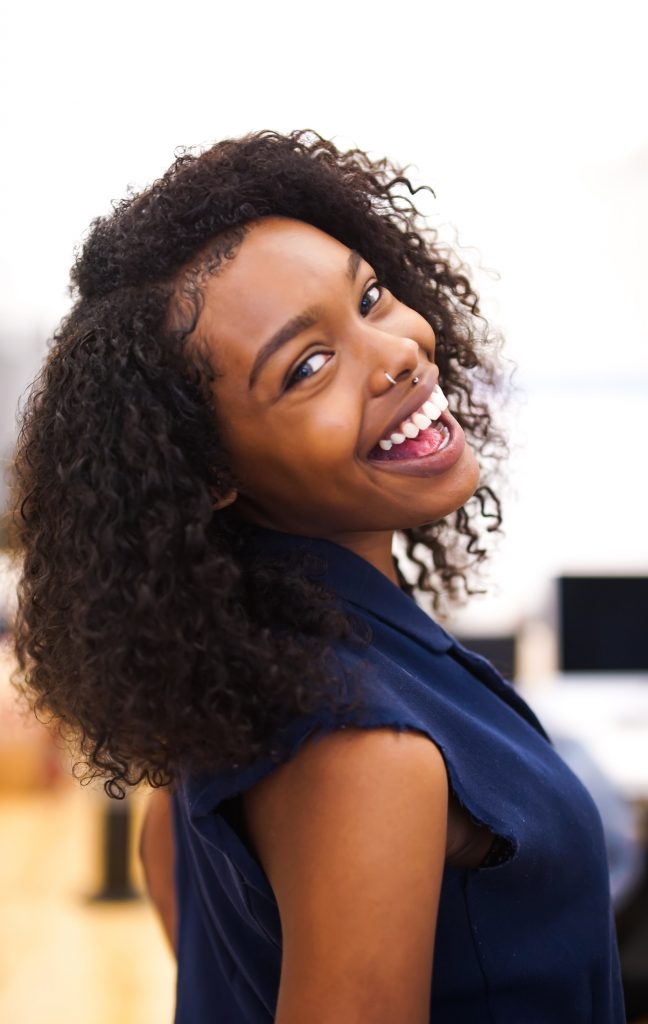 Black woman smiling after getting a root canal treatment.